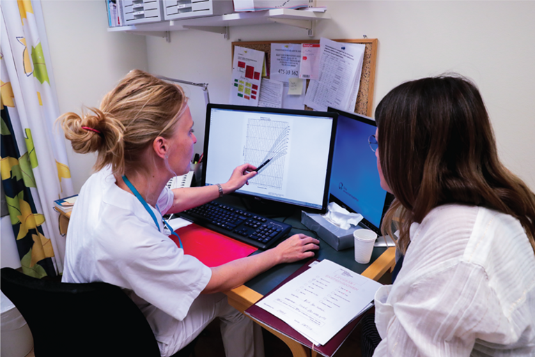 Two women sitting at a desk working on a computer.