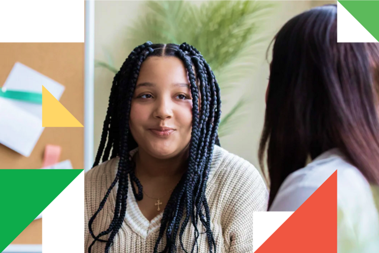 A woman with long braids talking to another woman.